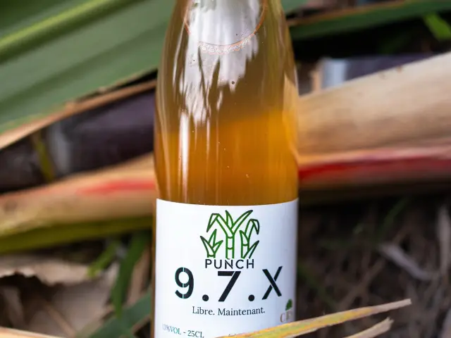 Bouteille de Punch 9.7.X posée sur des feuilles de canne à sucre